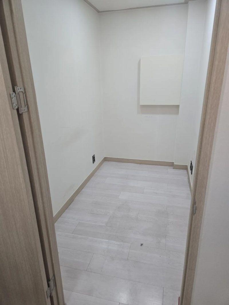 칸막이 문이 철거된 뒤 벽체와 마루 바닥재만 남은 좁은 방 내부