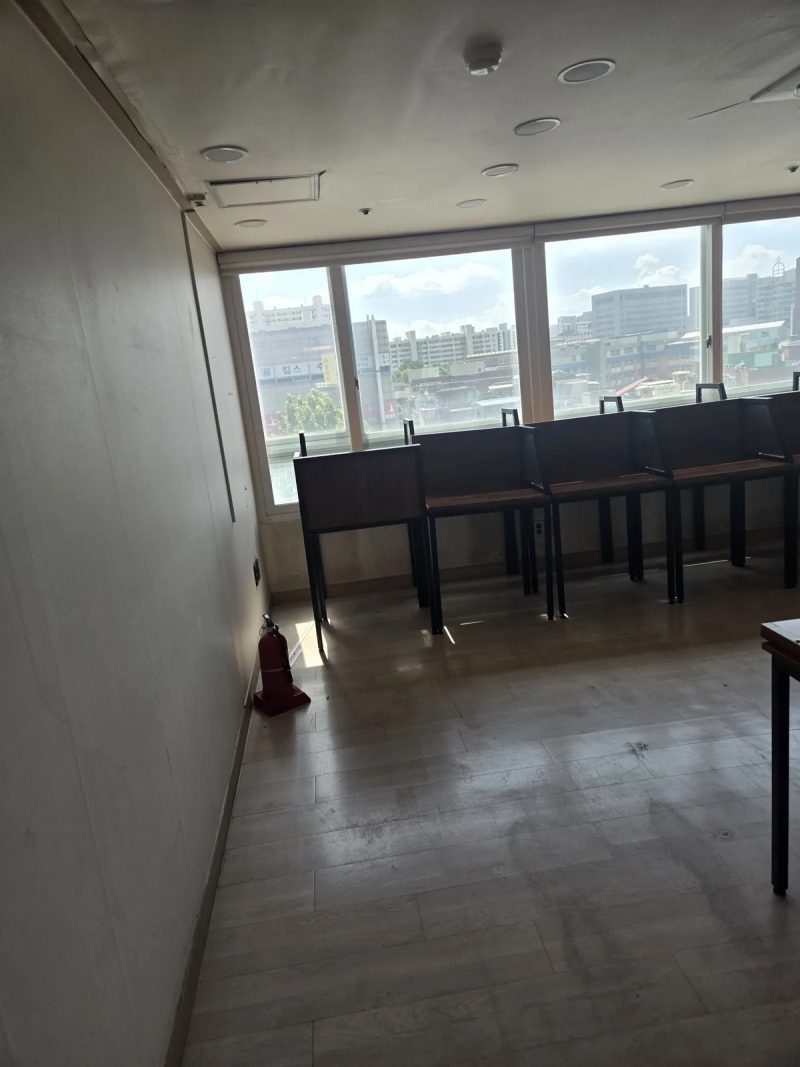 창가에 나란히 놓인 학원 책상 줄과 소화기